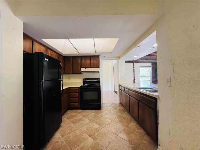 kitchen with sink, light tile patterned floors, black appliances, and dark brown cabinets