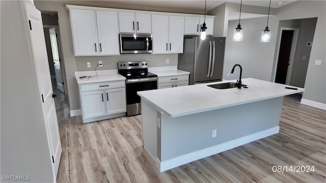 kitchen featuring white cabinetry, stainless steel appliances, an island with sink, sink, and hanging light fixtures