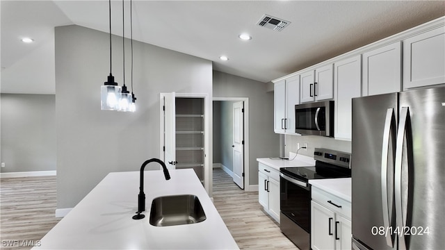 kitchen with lofted ceiling, hanging light fixtures, stainless steel appliances, and white cabinetry