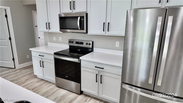 kitchen with light wood-type flooring, appliances with stainless steel finishes, and white cabinetry