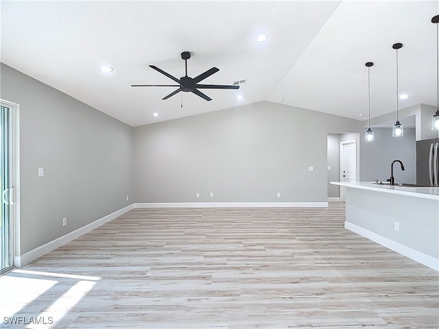 unfurnished living room with vaulted ceiling, sink, ceiling fan, and light hardwood / wood-style floors