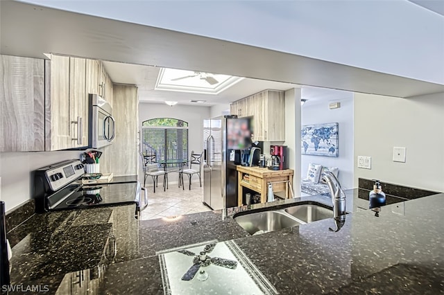 kitchen featuring sink, light brown cabinets, dark stone countertops, light tile patterned floors, and appliances with stainless steel finishes