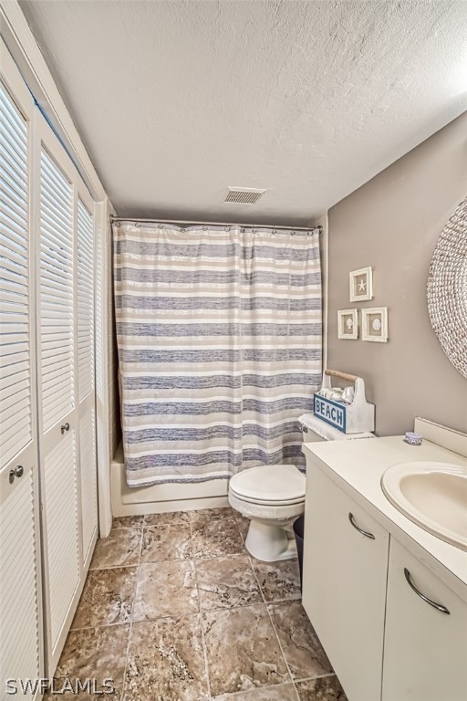 full bathroom with vanity, toilet, shower / bathtub combination with curtain, and a textured ceiling