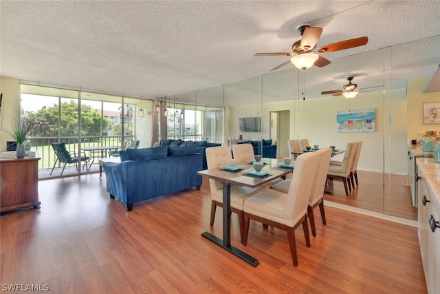 dining room featuring expansive windows, a textured ceiling, light hardwood / wood-style floors, and ceiling fan