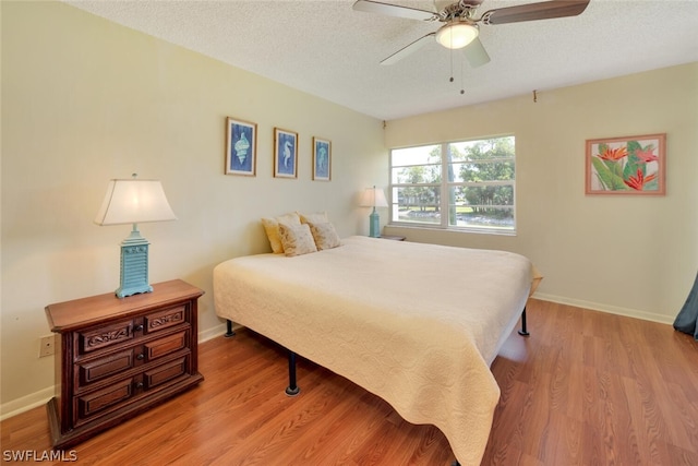 bedroom with a textured ceiling, light hardwood / wood-style floors, and ceiling fan