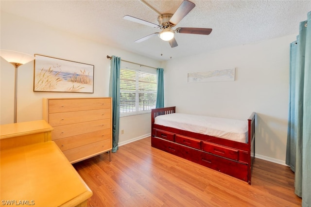 bedroom featuring ceiling fan, wood-type flooring, and a textured ceiling