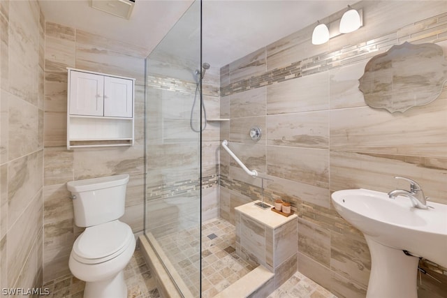 bathroom with tiled shower, sink, tile walls, and toilet