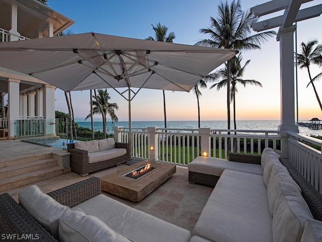 deck at dusk featuring an outdoor living space with a fire pit and a water view