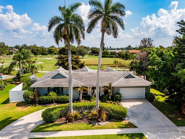 single story home with a tile roof, a garage, stucco siding, view of golf course, and concrete driveway