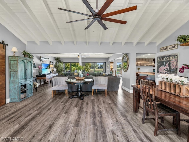 dining space featuring a ceiling fan, beamed ceiling, dark wood-style floors, and a barn door