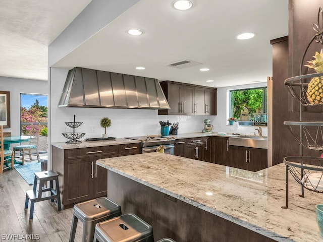 kitchen featuring light stone counters, dark brown cabinetry, light hardwood / wood-style floors, sink, and electric stove