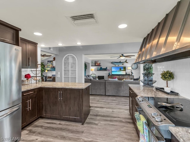 kitchen featuring light wood-type flooring, backsplash, stainless steel fridge, and ceiling fan