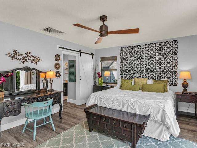 bedroom featuring a barn door, a ceiling fan, baseboards, wood finished floors, and visible vents