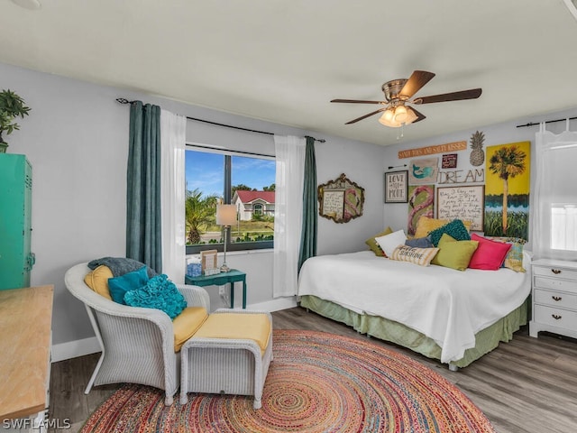 bedroom featuring ceiling fan, hardwood / wood-style flooring, and multiple windows