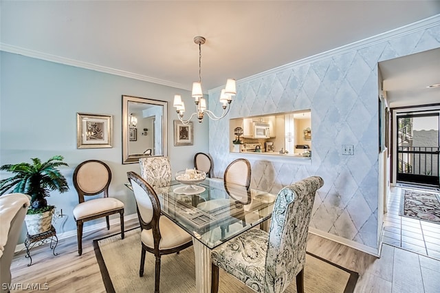 dining room with ornamental molding, a chandelier, and light hardwood / wood-style floors