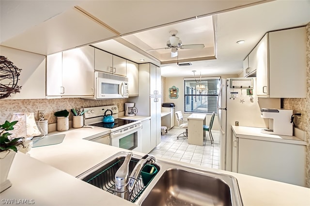 kitchen featuring ceiling fan, sink, white appliances, and a tray ceiling