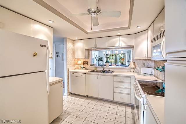 kitchen featuring sink, white cabinets, ceiling fan, a tray ceiling, and white appliances