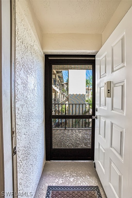 doorway to outside featuring a textured ceiling