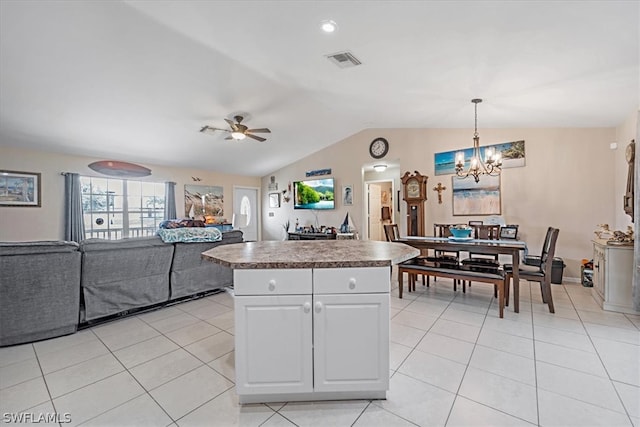 kitchen with lofted ceiling, white cabinets, ceiling fan with notable chandelier, decorative light fixtures, and a kitchen island