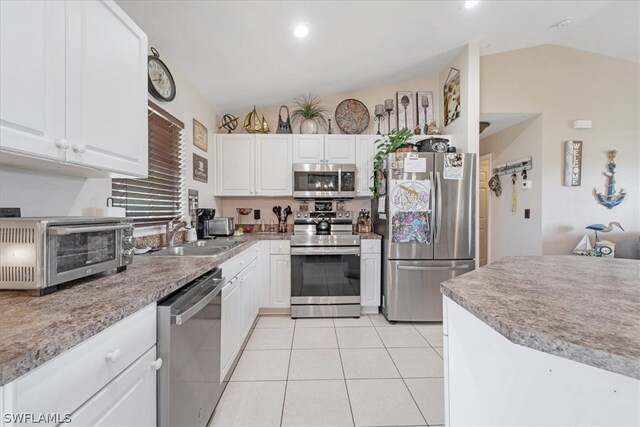 kitchen with lofted ceiling, sink, white cabinets, and appliances with stainless steel finishes