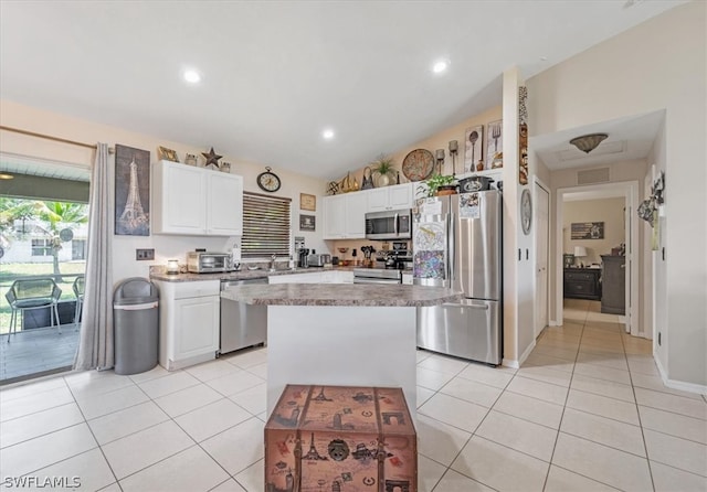 kitchen featuring white cabinets, stainless steel appliances, lofted ceiling, and a kitchen island