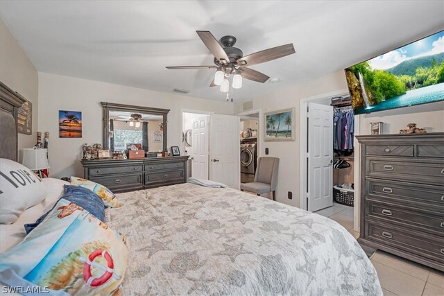 tiled bedroom with a walk in closet, washer / dryer, and ceiling fan