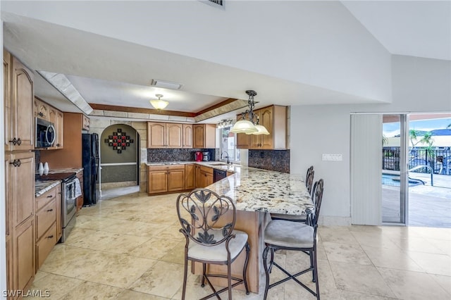 kitchen featuring kitchen peninsula, a kitchen bar, backsplash, black appliances, and hanging light fixtures