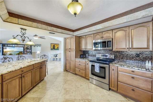 kitchen with pendant lighting, ceiling fan, light stone countertops, tasteful backsplash, and stainless steel appliances