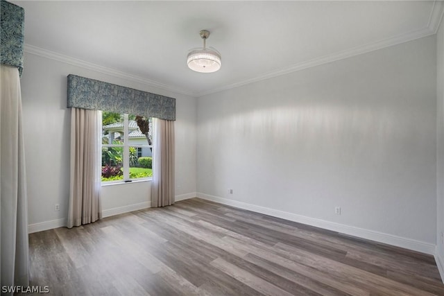 empty room featuring crown molding, baseboards, and wood finished floors