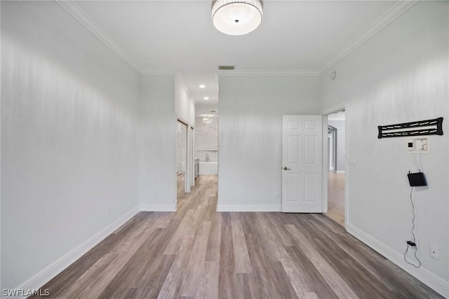 unfurnished room with ornamental molding, wood finished floors, visible vents, and baseboards