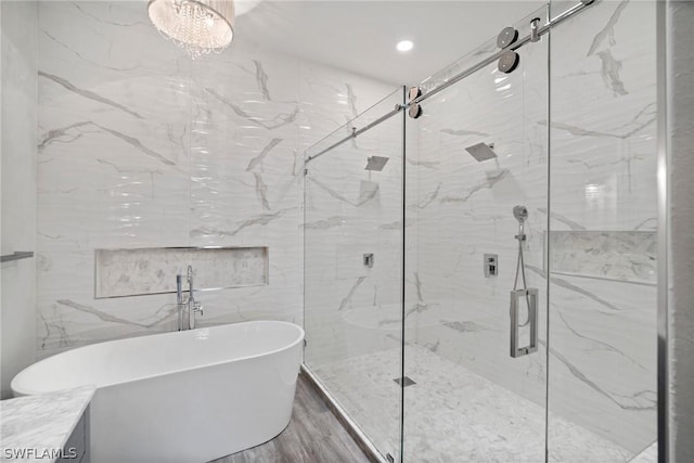 bathroom featuring wood finished floors, a freestanding tub, and a marble finish shower