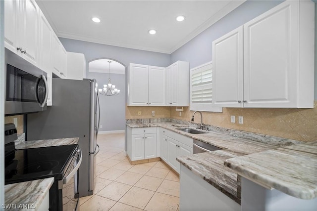 kitchen with arched walkways, white cabinets, ornamental molding, stainless steel appliances, and a sink