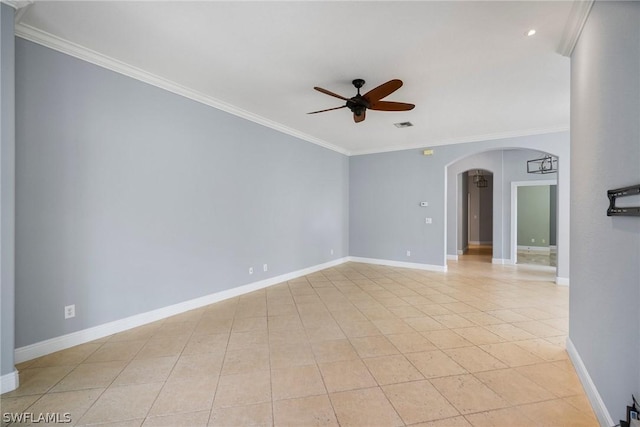 empty room featuring arched walkways, crown molding, light tile patterned floors, a ceiling fan, and baseboards