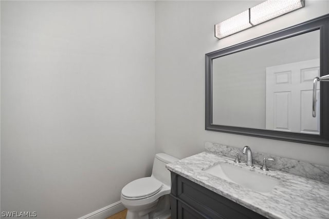 bathroom featuring toilet, vanity, and baseboards