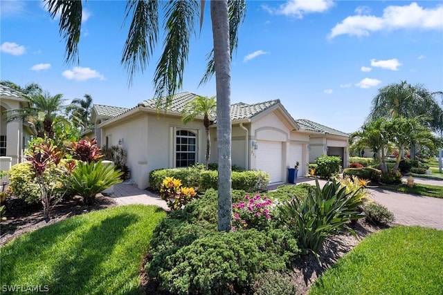 single story home with an attached garage, a tile roof, decorative driveway, and stucco siding