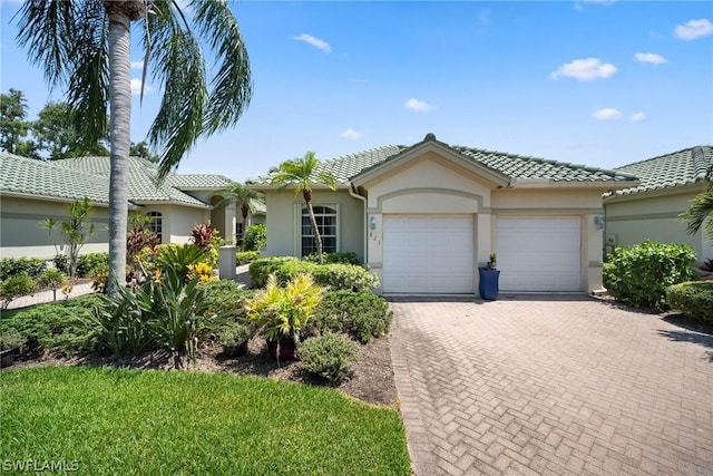 view of front of home featuring decorative driveway, a tiled roof, an attached garage, and stucco siding