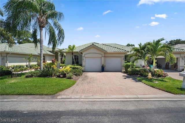 single story home with decorative driveway, stucco siding, a front yard, a garage, and a tiled roof