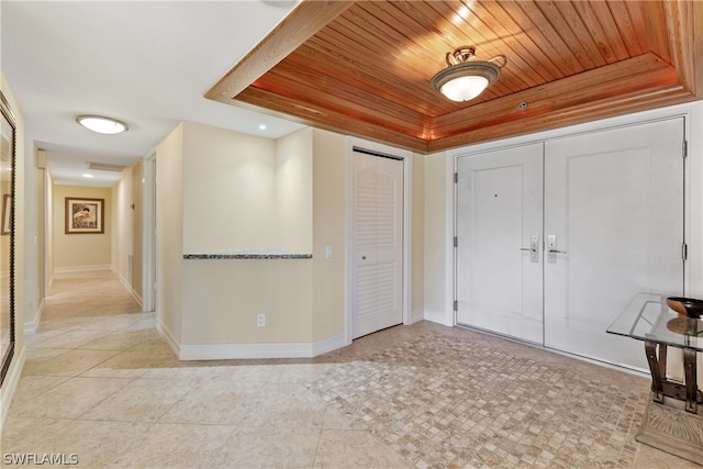 entrance foyer with a raised ceiling, wooden ceiling, and light tile patterned flooring