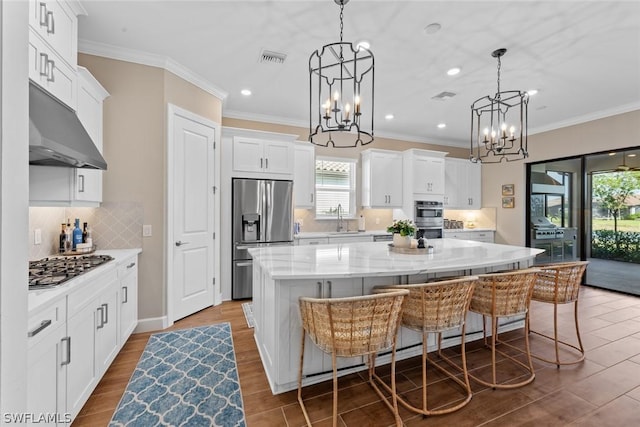 kitchen with a large island, sink, pendant lighting, white cabinets, and appliances with stainless steel finishes