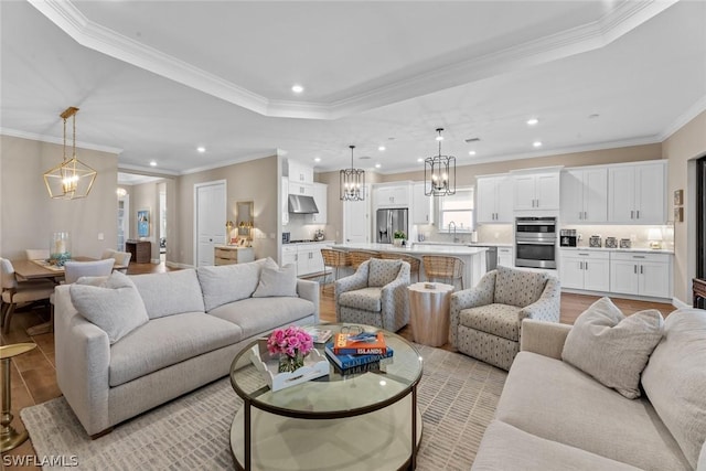 living room featuring light hardwood / wood-style floors, crown molding, and sink