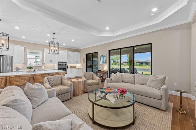 living room with an inviting chandelier, light hardwood / wood-style flooring, and crown molding