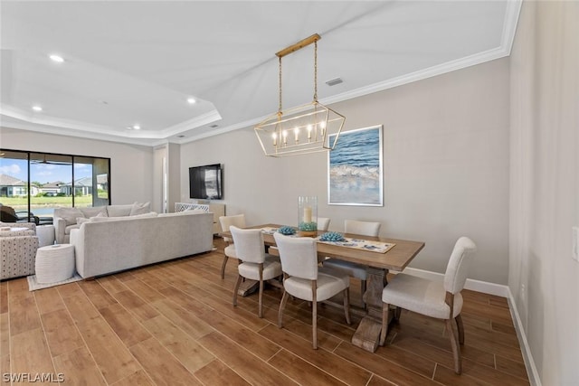 dining area with hardwood / wood-style floors, a notable chandelier, and ornamental molding