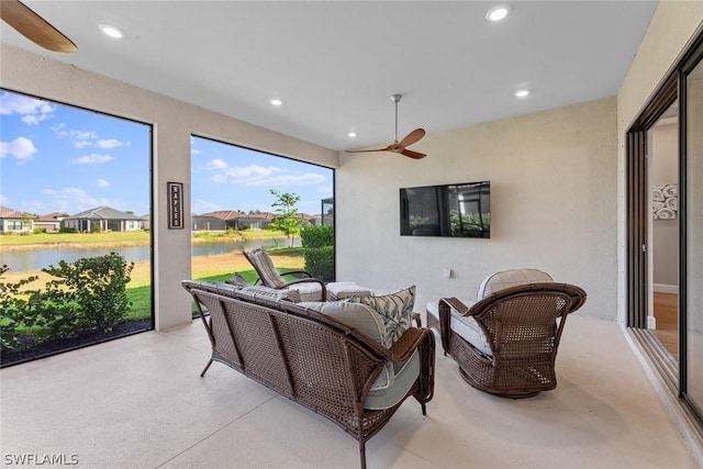 living room featuring ceiling fan and a water view