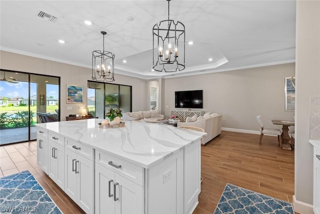 kitchen featuring a center island, light hardwood / wood-style flooring, light stone countertops, decorative light fixtures, and white cabinetry