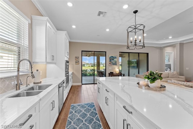 kitchen with white cabinets, a healthy amount of sunlight, light stone counters, and sink