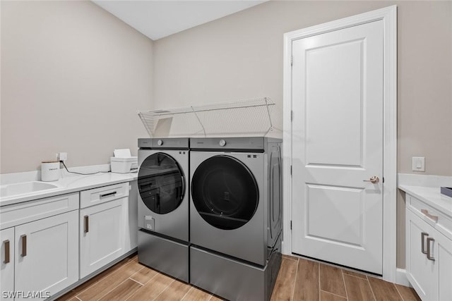 washroom with light hardwood / wood-style floors, independent washer and dryer, and sink