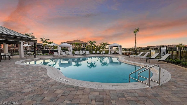 pool at dusk featuring a gazebo and a patio area