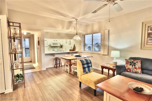 sitting room featuring ceiling fan with notable chandelier and light hardwood / wood-style flooring