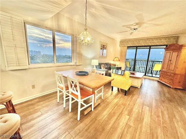 dining space featuring wood-type flooring and ceiling fan with notable chandelier