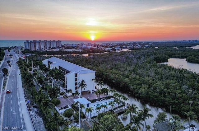 aerial view at dusk featuring a water view